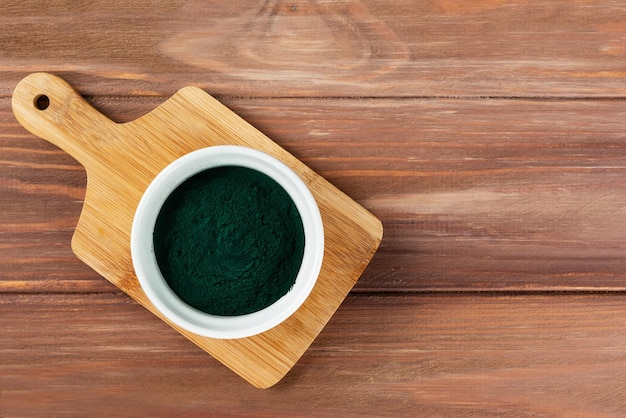 Polvere di spirulina in una ciotola su una tavola di legno Spazio per la copia della vista dall'alto con orientamento orizzontale