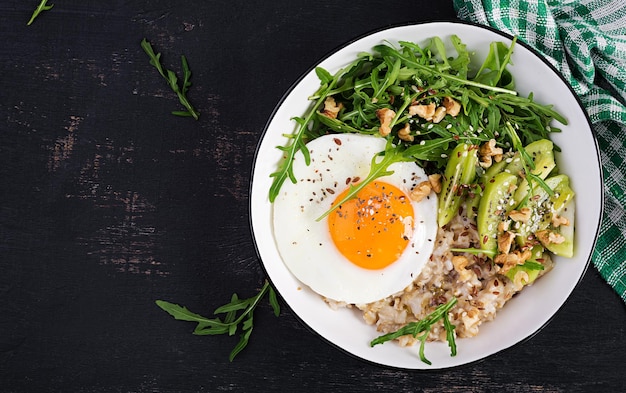 Porridge di farina d'avena per la colazione con uova arrostite kiwi rucola e semi di lino Colazione sana per abbassare il colesterolo Vista dall'alto piatto