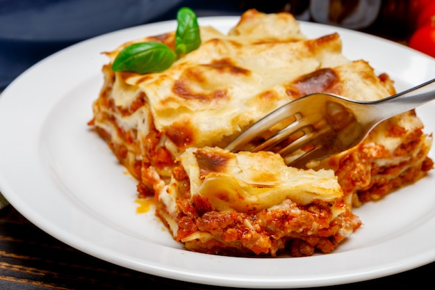 Porzione di primo piano delle lasagne al forno su backgound di legno