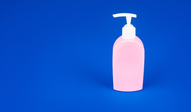 Presentazione del prodotto distributore di sapone. pubblicità di disinfettante senza marchio. abitudine quotidiana e cura della persona. cosmetici di bellezza per la cura della pelle su sfondo blu. articoli da toeletta per l'igiene.