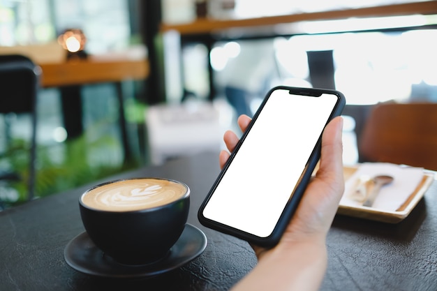 Primo piano di una donna che utilizza uno smart phone mobile vuoto e una carta di credito che invia massaggi nella caffetteria