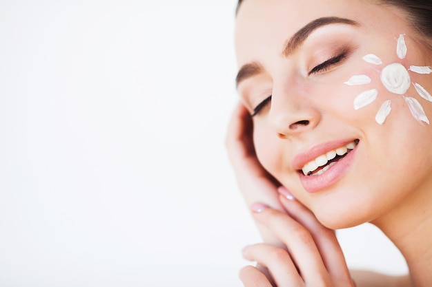 Ragazza di bellezza che applica crema solare sul viso