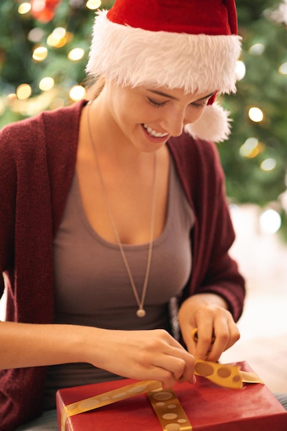 Regalo di Natale e giovane donna felice che apre una scatola vicino all'albero per celebrare le vacanze Felicità eccitata e ragazza dal Canada con regalo di Natale che indossa divertimento festivo e cappello tradizionale a casa