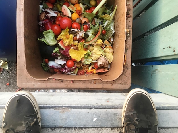 Foto sezione bassa dell'uomo in piedi sopra il bidone della spazzatura