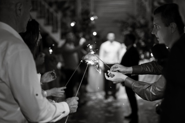 Sparklers al matrimonio degli sposi nelle mani di ospiti gioiosi