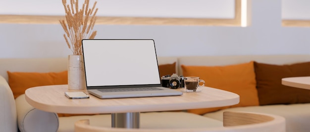 Spazio di coworking moderno in una caffetteria con mockup di schermo vuoto per computer portatile su un tavolino da caffè