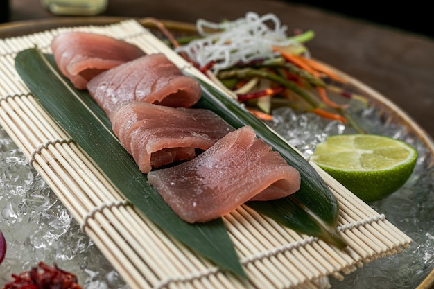 Sushi su foglie verdi su legno con sfondo di verdure al limone