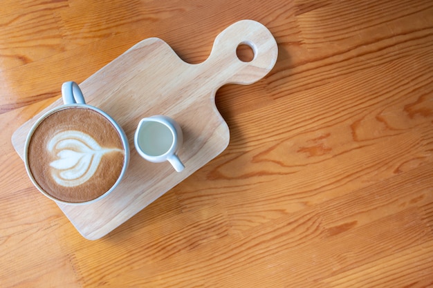 Tazza di caffè del latte con arte del latte sulla tavola di legno in caffetteria.