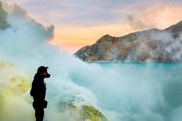 Foto turista nel cratere di un vulcano sulfur accoppia il lago blu vulcanico e l'alba rosa un viaggio pericoloso nella foce di un vulcano attivo gunung ijen indonesia isola di giava