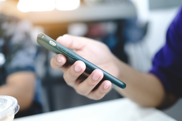 Un uomo in possesso di un telefono intelligente, vista laterale al caffè.