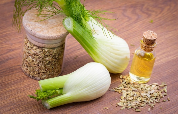 Foto una bottiglia di olio essenziale di finocchio con rametti di finocchio verde fresco e semi di finocchio sullo sfondo