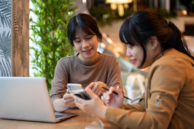 Foto una donna sta parlando e condividendo qualcosa sul suo telefono con la sua amica mentre sono seduti insieme in un caffè