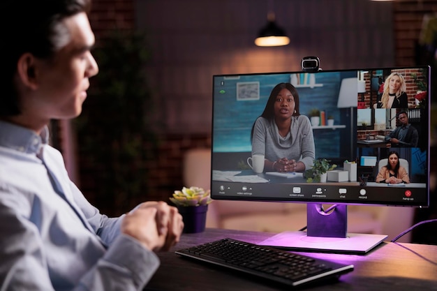 Uomo asiatico che parla con i colleghi in videoconferenza, partecipa a riunioni di lavoro online in teleconferenza. Utilizzo della webcam sul computer per chattare con persone su connessione videochiamata Internet.