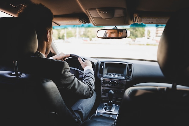 Vista posteriore dell&#39;uomo d&#39;affari che guida l&#39;auto