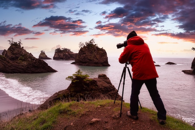 Foto vista posteriore di un uomo che fotografa sulla spiaggia contro il cielo