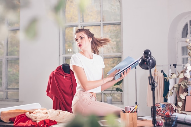 Foto grátis a estilista feminina trabalhando em um estúdio, sentada na mesa