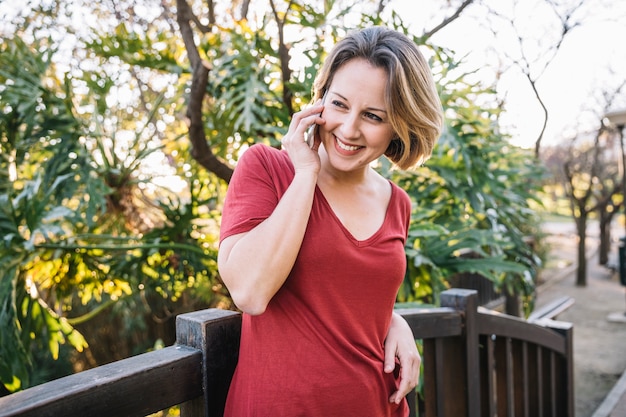 Foto grátis alegre mulher falando no telefone perto da cerca