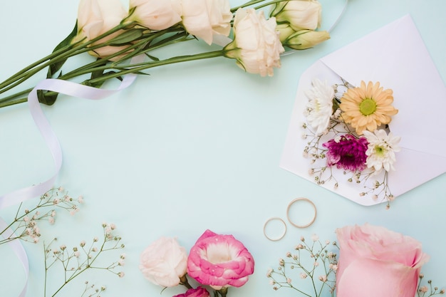 Foto grátis alianças de casamento e decoração de flores sobre fundo azul pastel