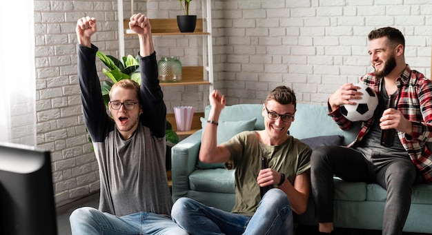 Foto grátis amigos do sexo masculino alegres assistindo esportes na tv com futebol e cerveja