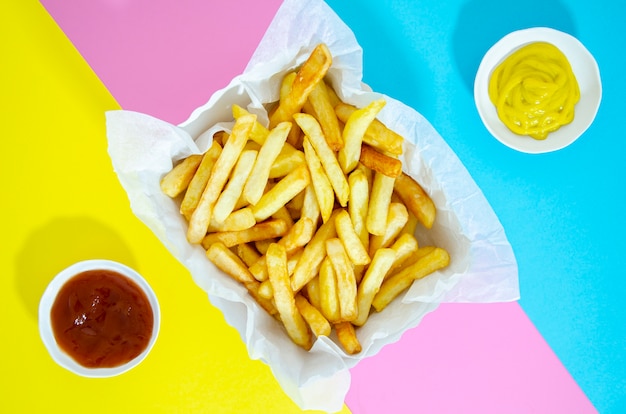 Foto grátis apartamento leigos de batatas fritas no fundo colorido