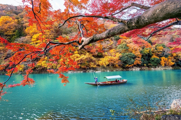 Foto grátis barqueiro rebatendo o barco no rio. arashiyama na temporada de outono ao longo do rio em kyoto, japão