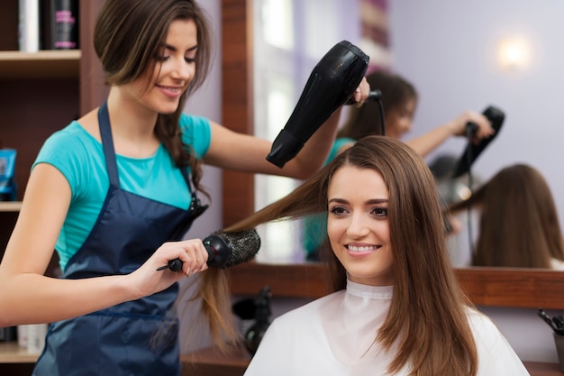 Cabeleireira usando escova e secador de cabelo