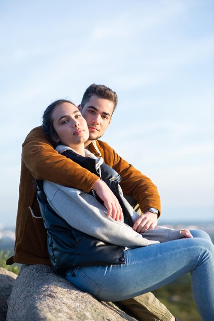 Casal carinhoso descansando depois de caminhar no outono. Homem e mulher em roupas casuais, sentado no pico, olhando para a câmera. Natureza, atividade, conceito de hobby