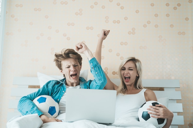 Foto grátis casal feliz assistindo futebol na cama