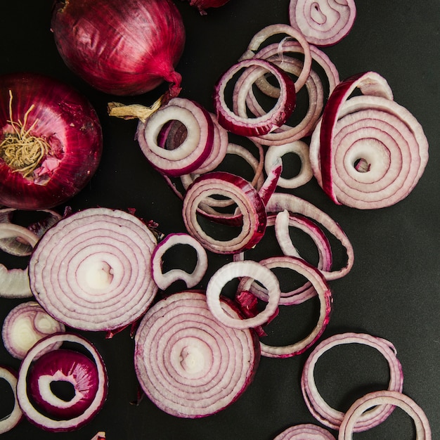 Foto grátis cebola inteira e fatias na parte superior da cozinha preta