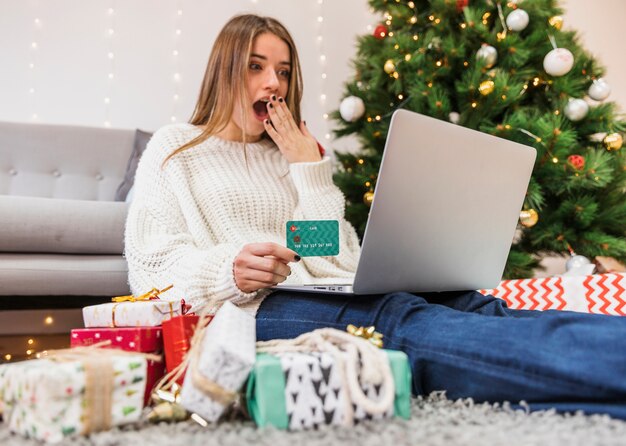 Chocado mulher compras on-line na árvore de Natal