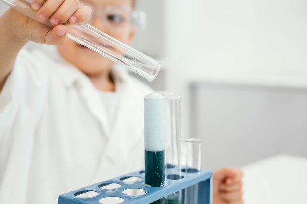 Foto grátis cientista sorridente no laboratório com tubos de ensaio fazendo experiências