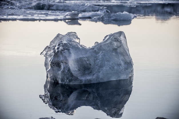 Foto grátis close de um pedaço de gelo flutuando no oceano e refletido em jokulsarlon, islândia