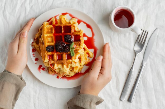 Close-up de mãos segurando um prato com waffles