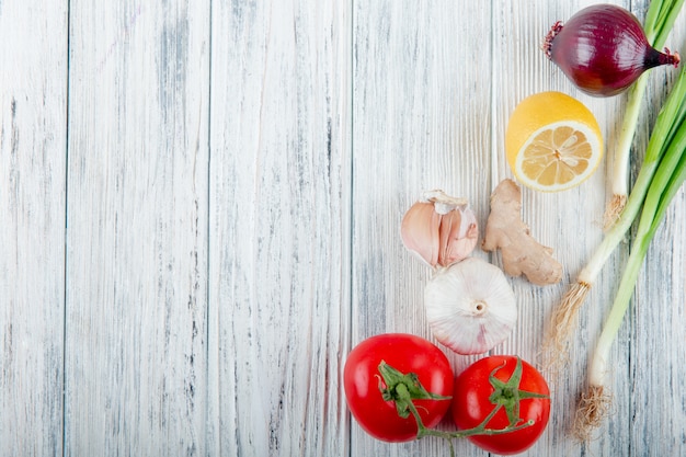 Foto grátis close-up vista de legumes como cebola cebolinha gengibre alho tomate com limão no fundo de madeira com espaço de cópia