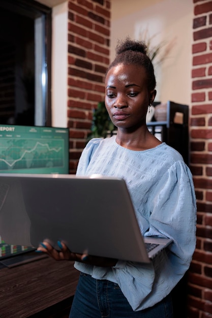 Foto grátis comerciante profissional da empresa de fundos de hedge com laptop enquanto revisa estatísticas financeiras ao vivo no espaço de trabalho do escritório. agente do mercado de ações forex em frente à estação de trabalho multi monitor.