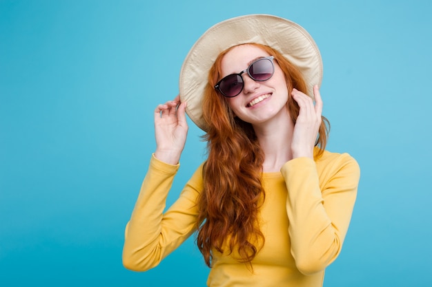 Foto grátis conceito de viagem - close up retrato jovem e bonita menina redhair atraente com chapéu de moda e sorvete sorrindo. fundo pastel azul. copie o espaço.