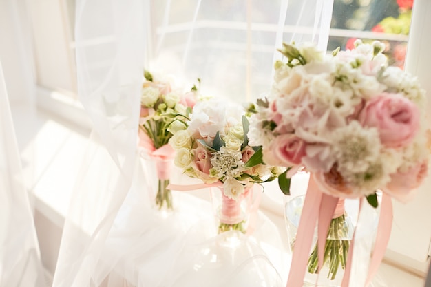 Foto grátis decoração do casamento. buquê de rosa cor de rosa brilhante para uma noiva e damas de honra diante de uma janela