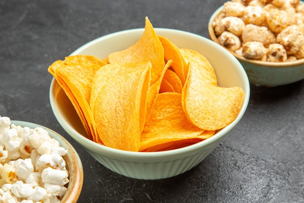 Foto grátis deliciosos cips de queijo com diferentes petiscos em piso escuro de frente