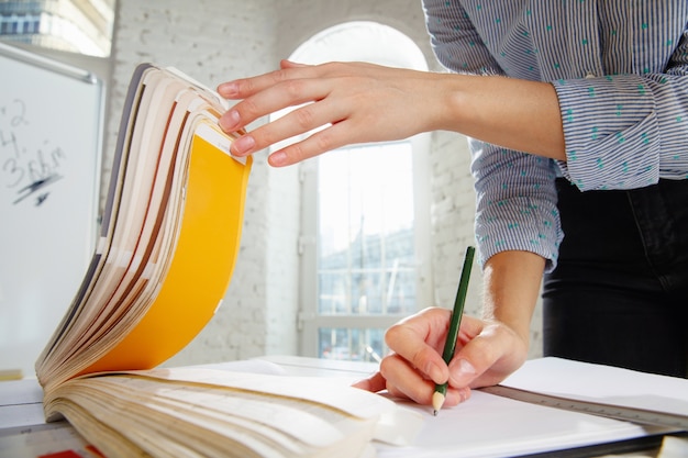 Foto grátis designer de interiores profissional ou arquiteto trabalhando com paleta de cores, desenhos de quartos em escritórios modernos. jovem modelo feminino planejando futuro apartamento ou casa, escolhendo cores e derocation.