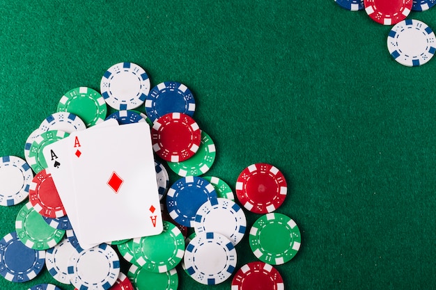 Foto grátis dois ases jogando cartas e fichas na mesa de poker verde