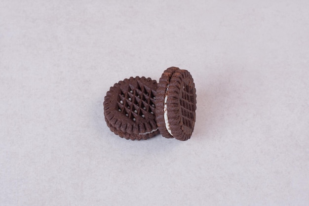 Foto grátis dois, pequenos biscoitos de chocolate doce na mesa branca.