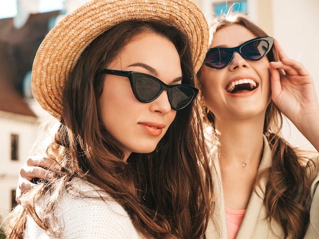 Foto grátis duas lindas garotas hippie sorridentes com um casaco e suéter branco da moda