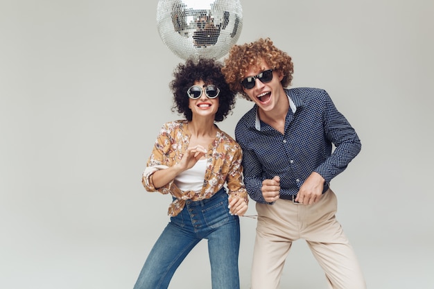 Foto grátis emocional sorridente retrô amando o casal dançando perto de bola de discoteca.