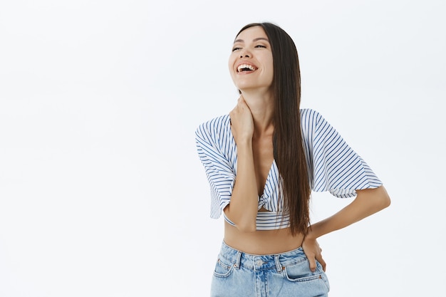 Foto grátis esposa adulta atraente, alegre e despreocupada, de blusa curta e jeans rindo alto de diversão