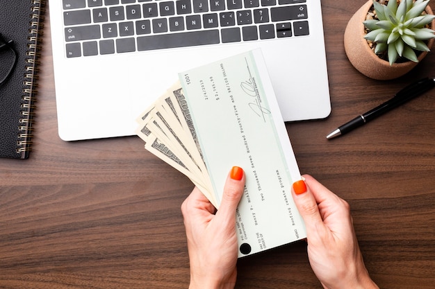 Foto grátis feche as mãos segurando dinheiro e cheque