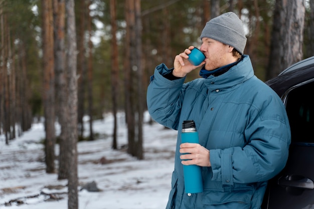 Foto grátis feche o homem desfrutando de bebida quente durante a viagem de inverno