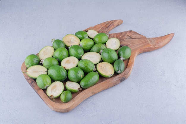 Foto grátis feijoas empacotadas em uma bandeja de madeira com fundo de mármore.