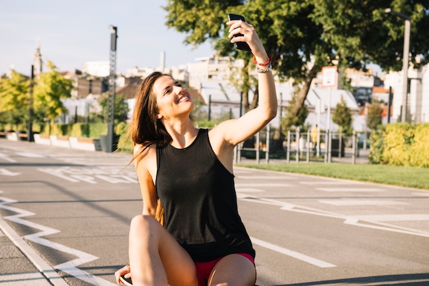 Foto grátis feliz, mulher senta-se, ligado, skateboard, levando, selfie, com, cellphone