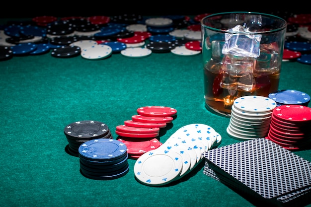 Foto grátis fichas de poker e copo de uísque na mesa de poker verde