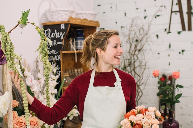 Foto grátis florista alegre que mostra flores na loja